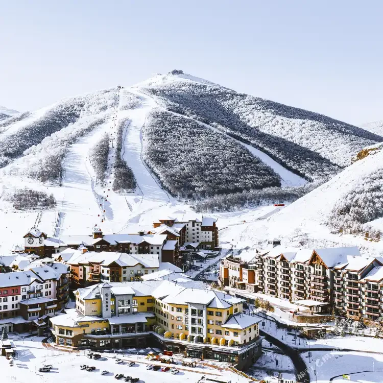 Snow-covered ski slopes and alpine-style village buildings in Chongli